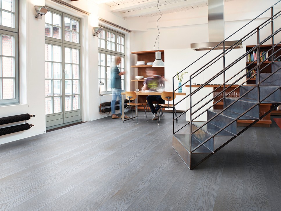 Wohnbereich mit gro&szlig;fl&auml;chigem Echtholzboden in Graut&ouml;nen, offener Treppe und modernem Interieur